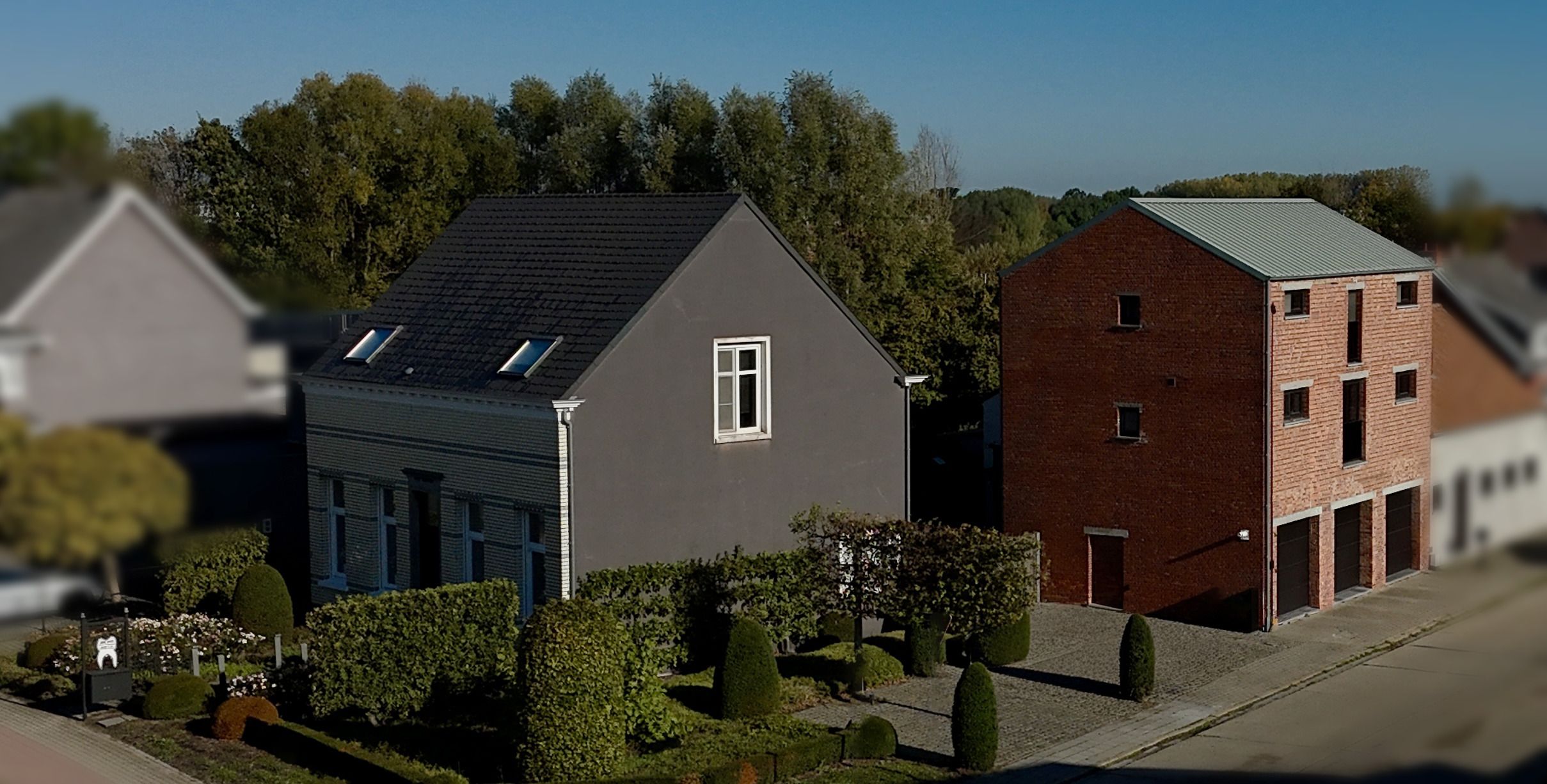 Luchtbeeld van het pand van Retzius in Lier: een lichtgrijs huis met een donker dak naast een bakstenen gebouw met een groen dak.